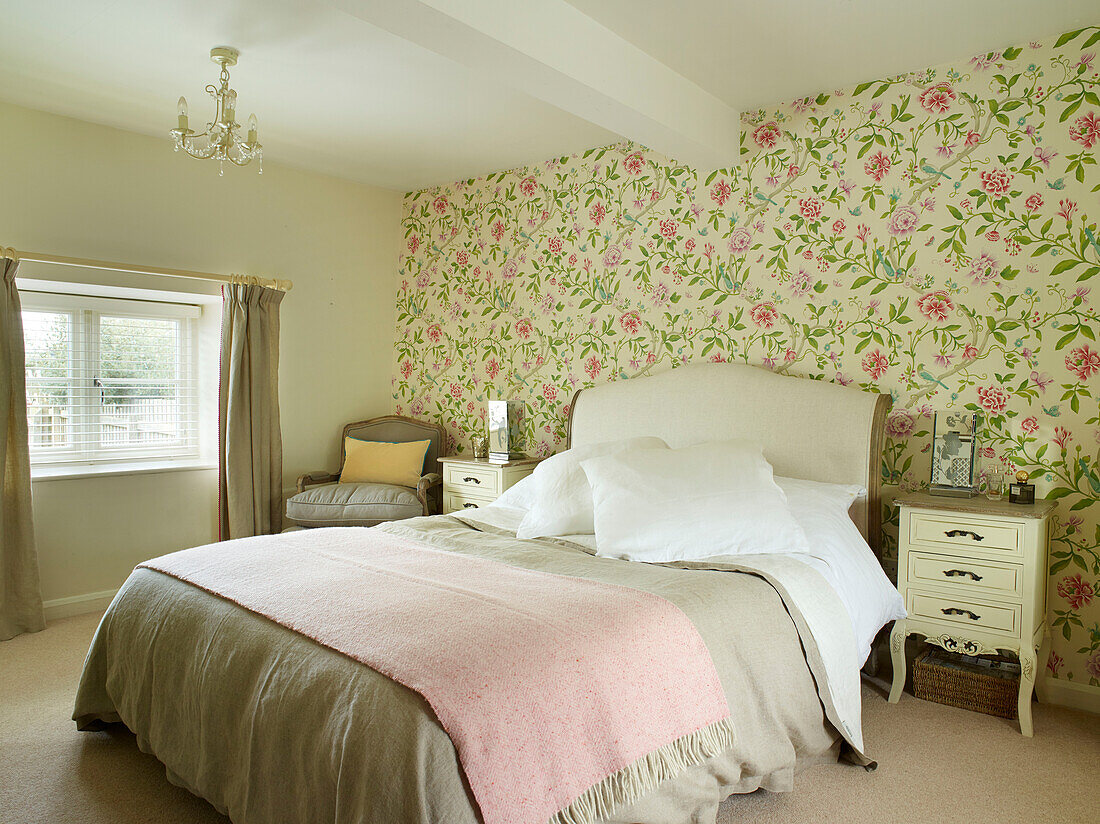 Rosa Decke auf einem Doppelbett mit Blumentapete in einem Landhaus in Oxfordshire, England, Vereinigtes Königreich