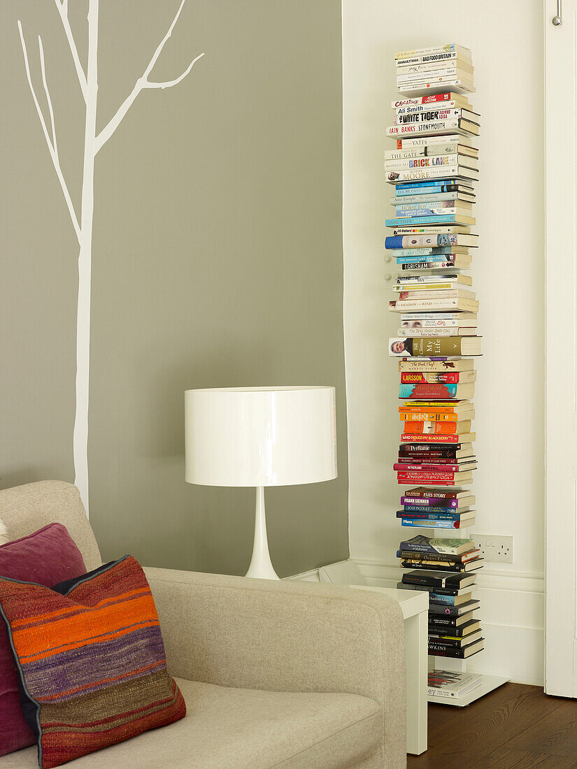 Book storage with lamp and sofa in living room of London home, UK