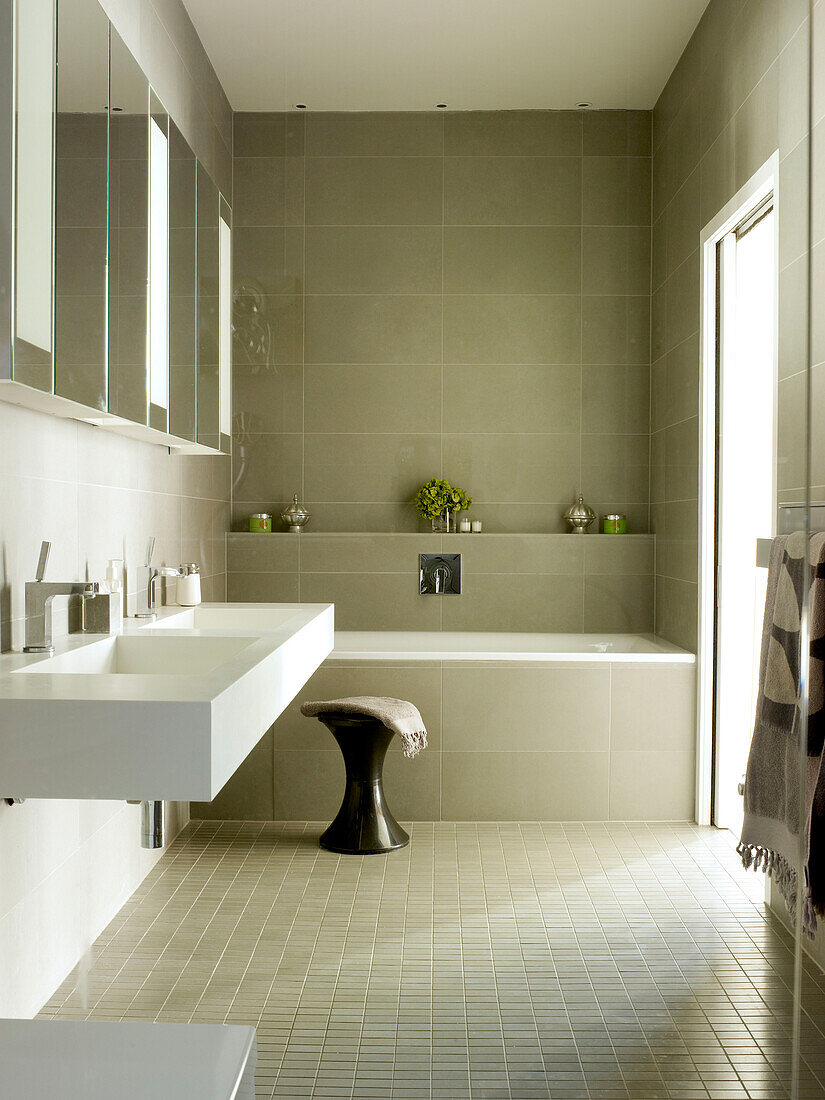 Spiegelschränke über Doppelwaschbecken in gefliestem Badezimmer eines Londoner Hauses, UK