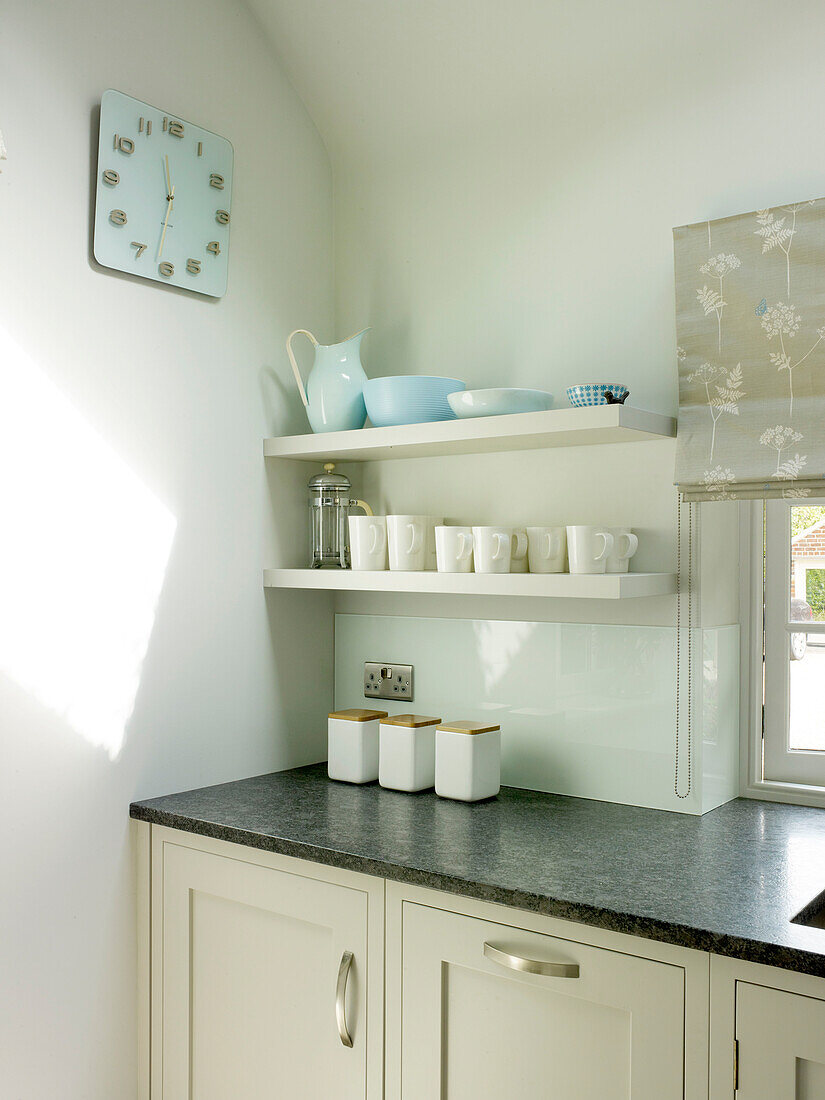 Light blue clock with kitchenware on open shelving in Nottinghamshire home England UK
