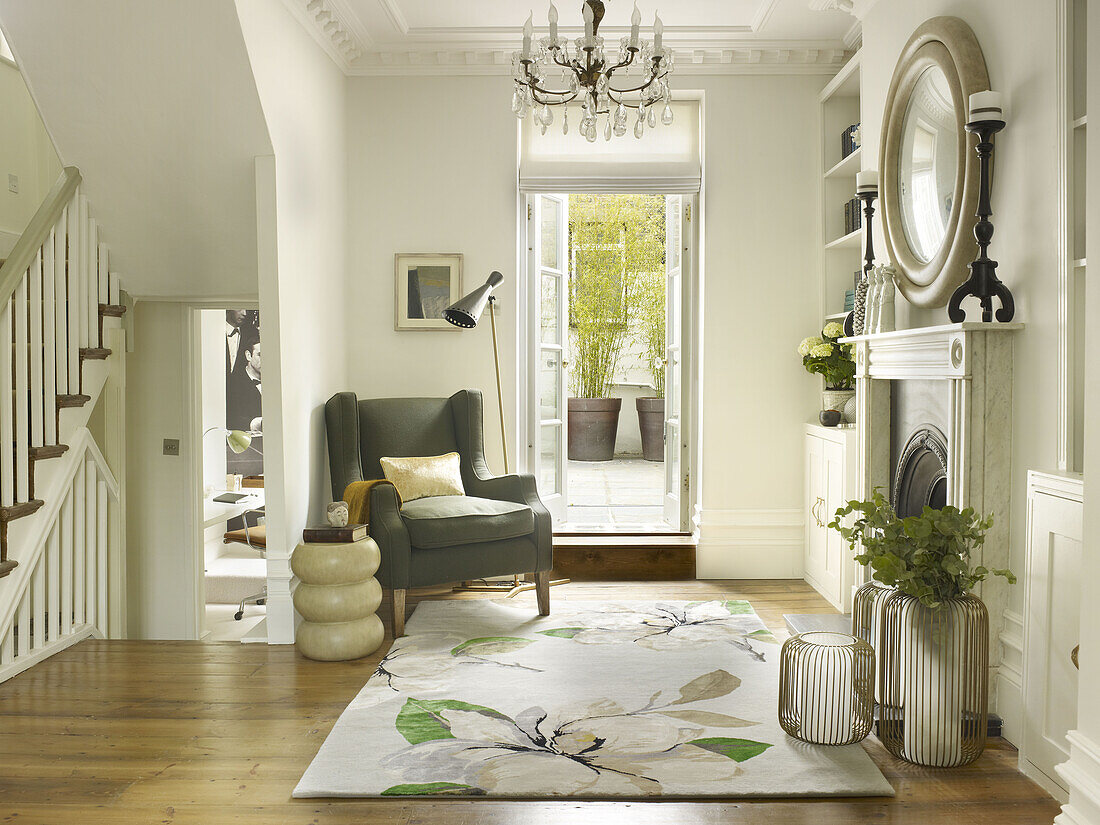 Grey armchair in open plan hallway with fireplace in North London townhouse England UK