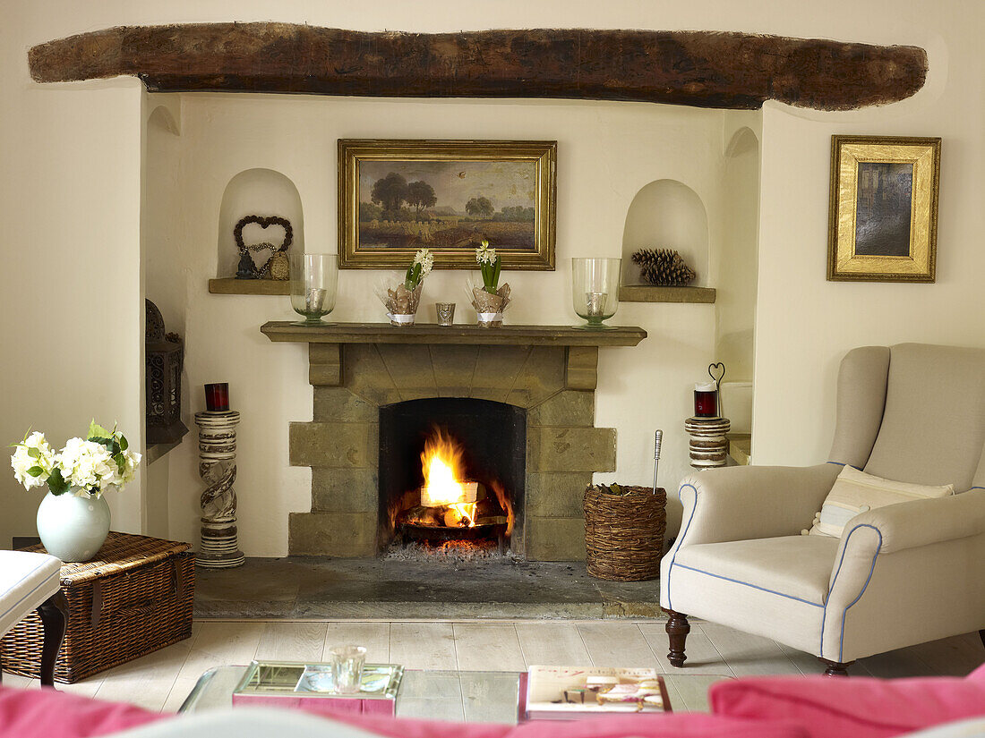Armchair at lit fireplace in living room of Nottinghamshire home England UK