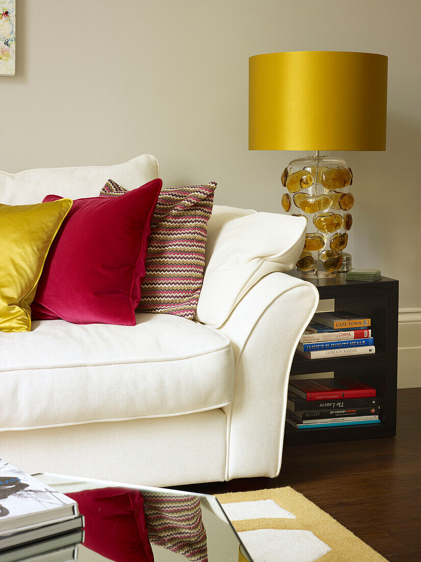 Goldmetallic-Lampenschirm mit roten Kissen auf weißem Sofa im Wohnzimmer eines Stadthauses in Little Venice London England UK