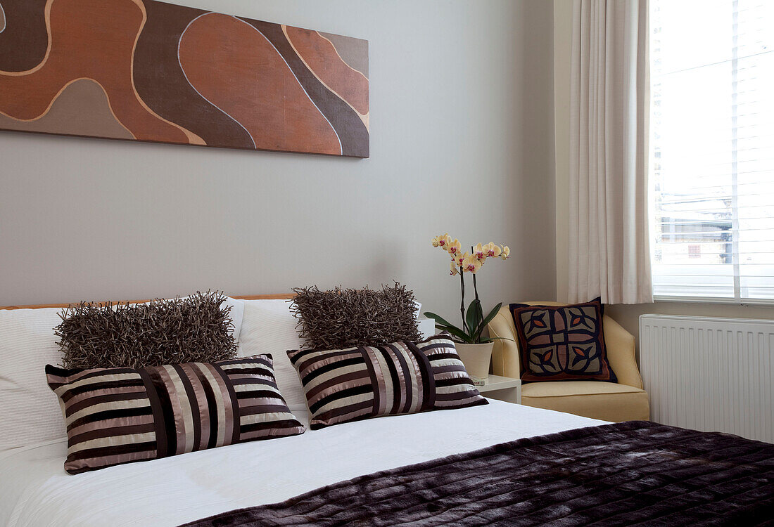 Kissen mit braunen Leinwandbildern im Schlafzimmer eines modernen Hauses in London, England, UK