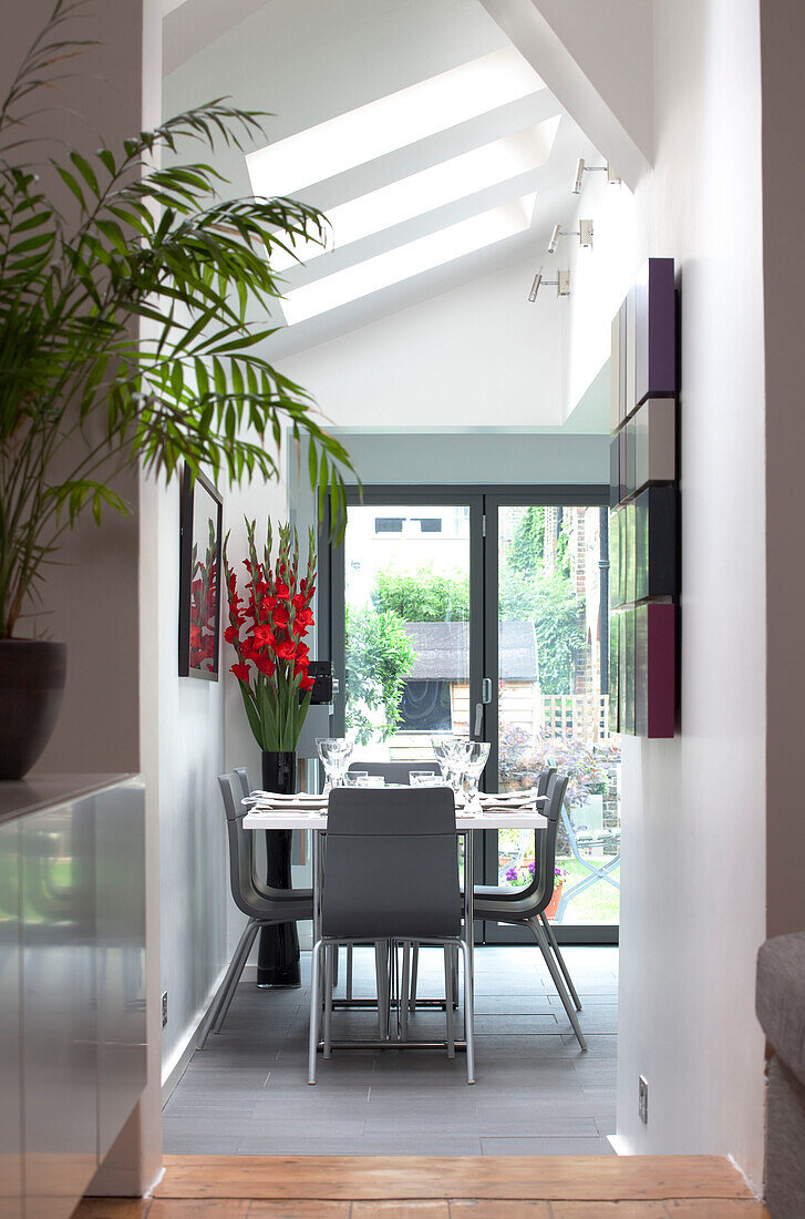 View through hallway yo grey dining suite below skylight windows in contemporary London home, England, UK