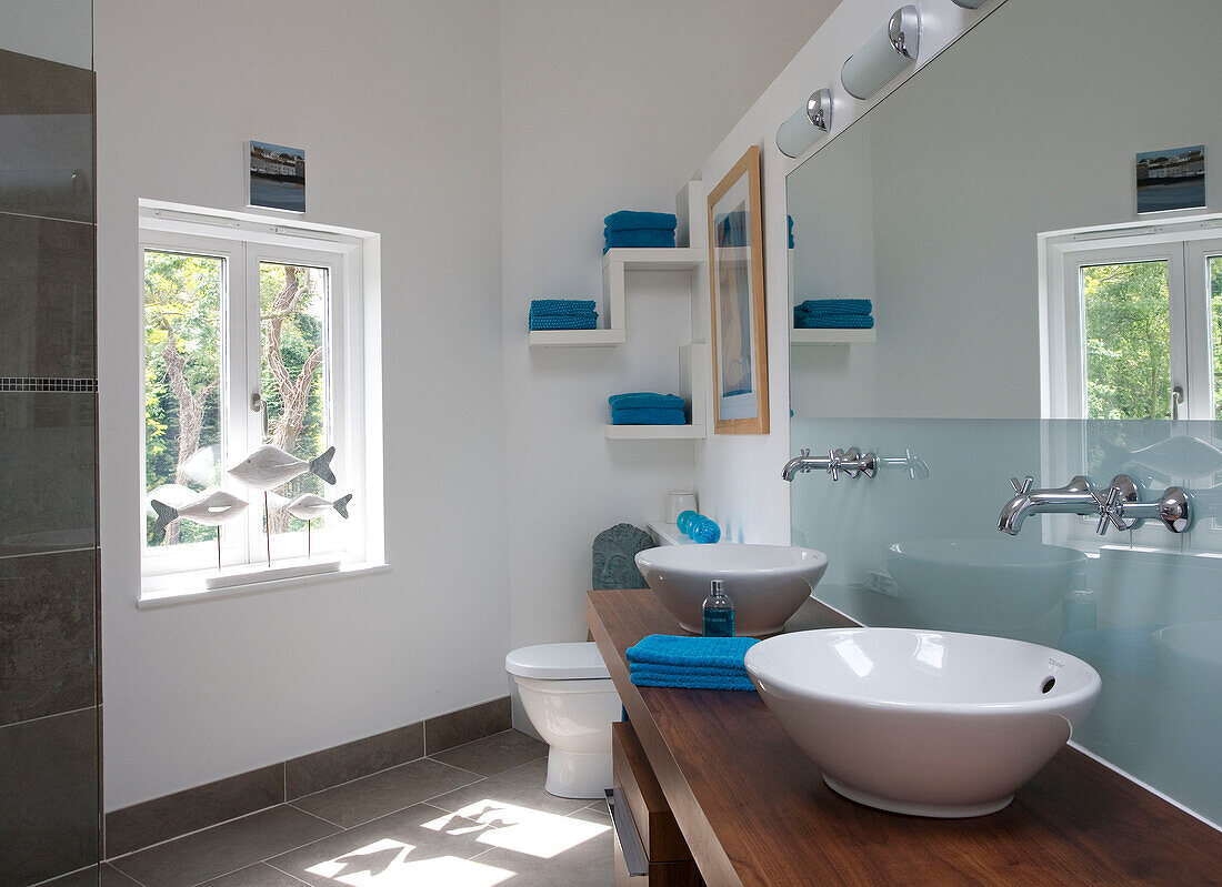 Doppelwaschbecken in sonnenbeschienenem Badezimmer in Cambridgeshire mit Fischstatuen auf der Fensterbank UK