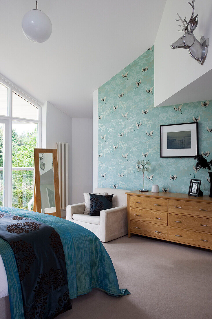 Silberner Tierkopf in einem Schlafzimmer in Cambridgeshire mit türkisfarbener Tagesdecke und gemusterter Tapete UK