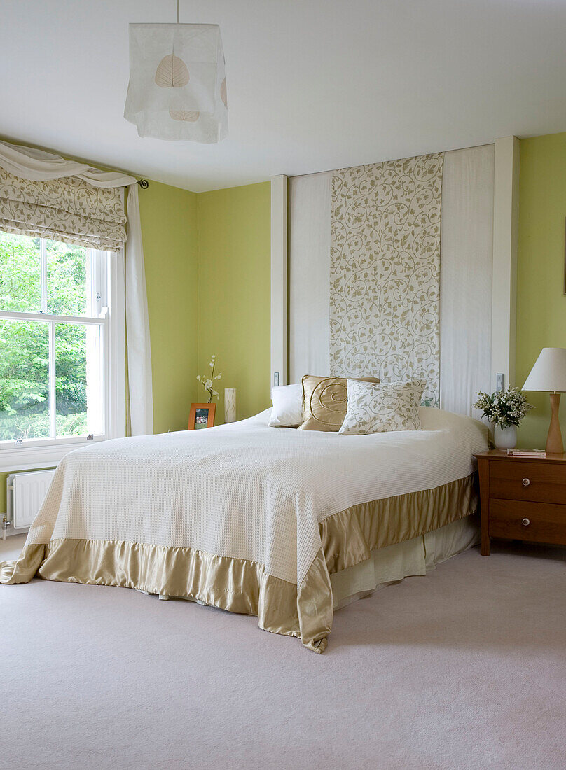 Doppelbett mit Kissen und Kopfteil mit Blättermuster in einem Haus in Cambridgeshire, Großbritannien
