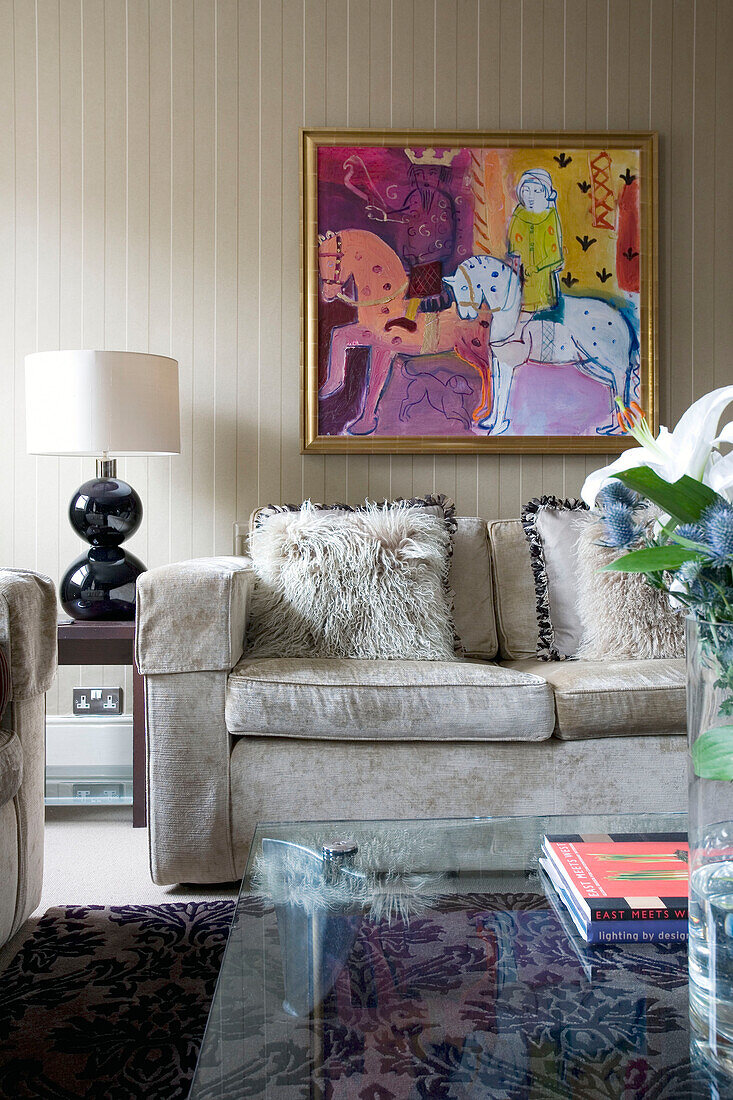 Straußenfederkissen auf beigem Sofa unter moderner Kunst