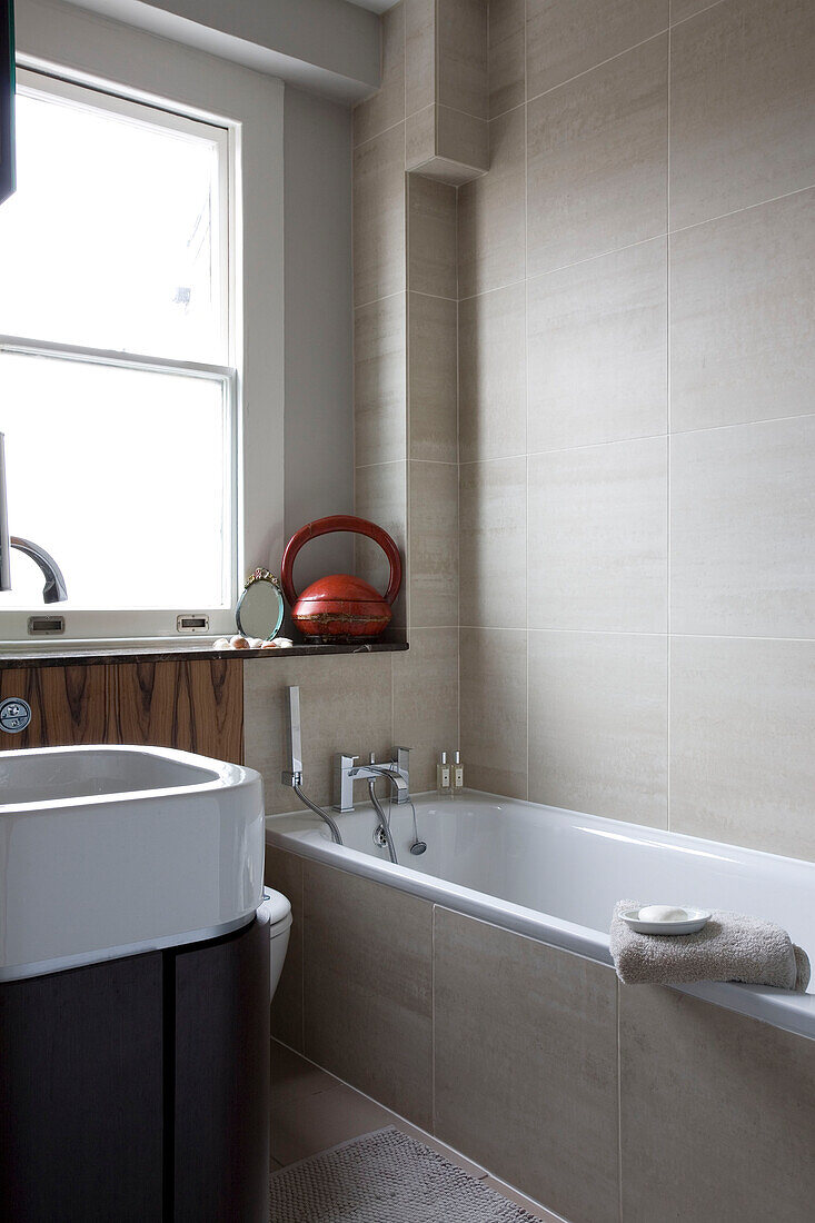 Cremefarben gefliestes Badezimmer mit Waschbecken und Sprossenfenster