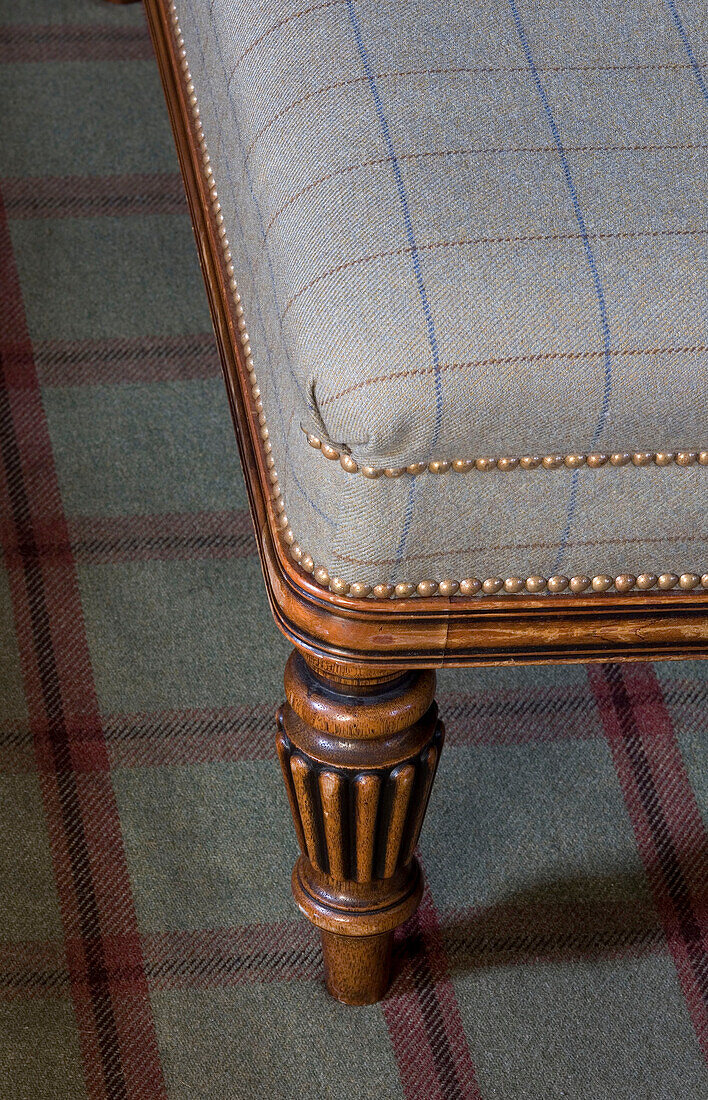 Geschnitztes hölzernes Möbelbein mit Tartan-Stoff in einem schottischen Haus UK