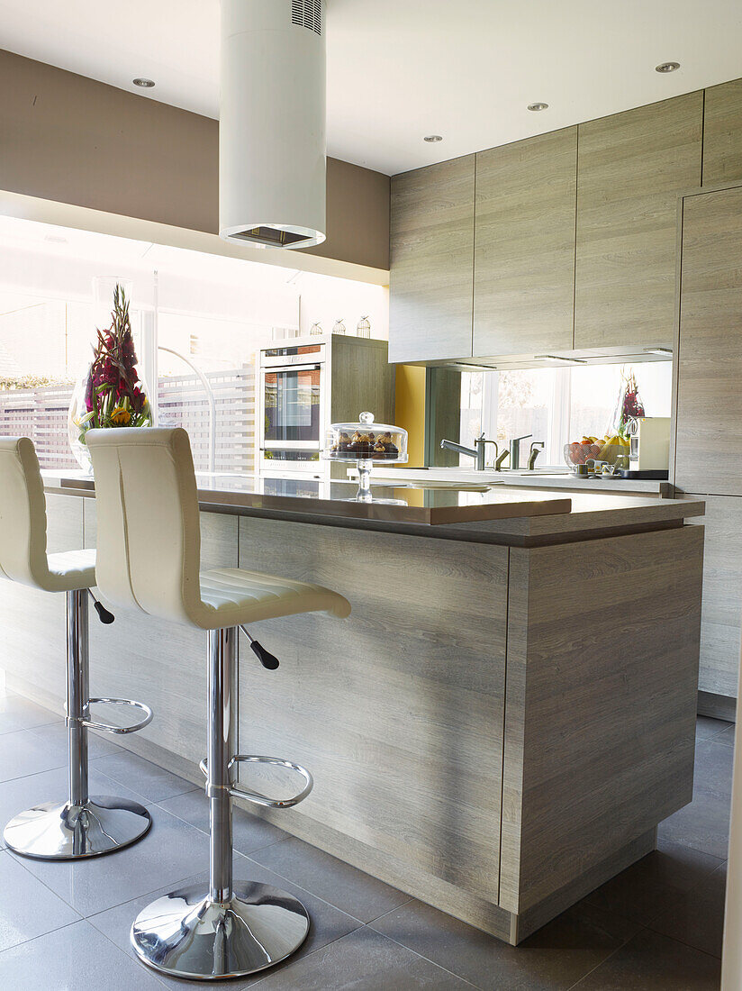 White leather barstools at breakfast bar in Manchester kitchen, England, UK