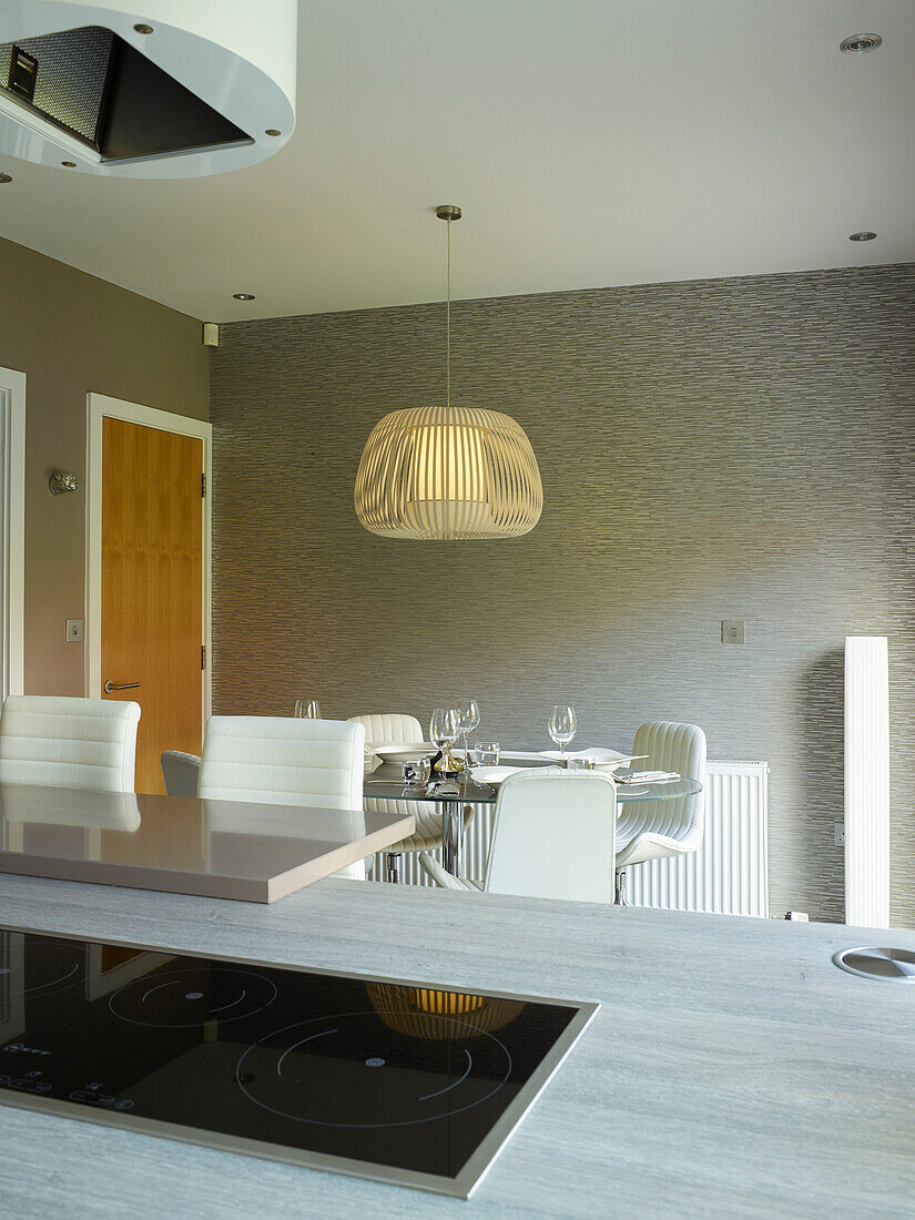 Pendant shade above dining table in open plan kitchen with electric hob, Manchester home, England, UK