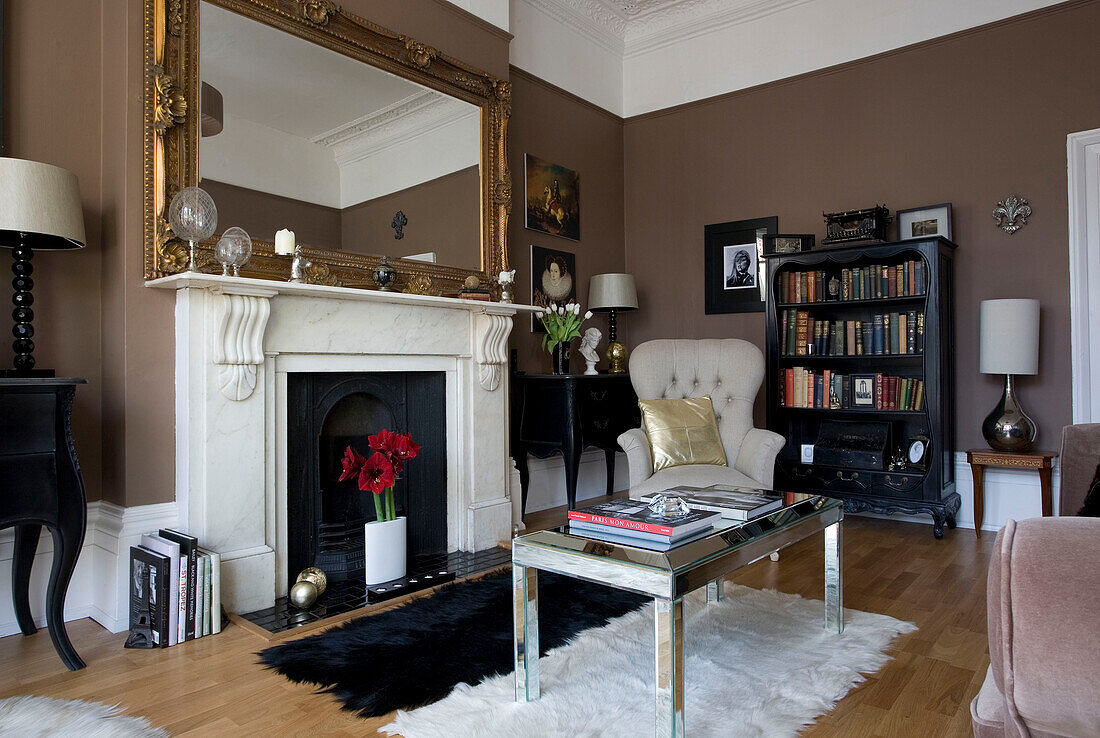 Mirrored coffee table at fireplace with oversized gilt mirror in Hove home East Sussex UK