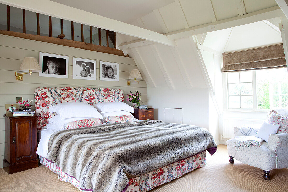 Fur throw on floral patterned bed in timber framed Kent cottage, England, UK