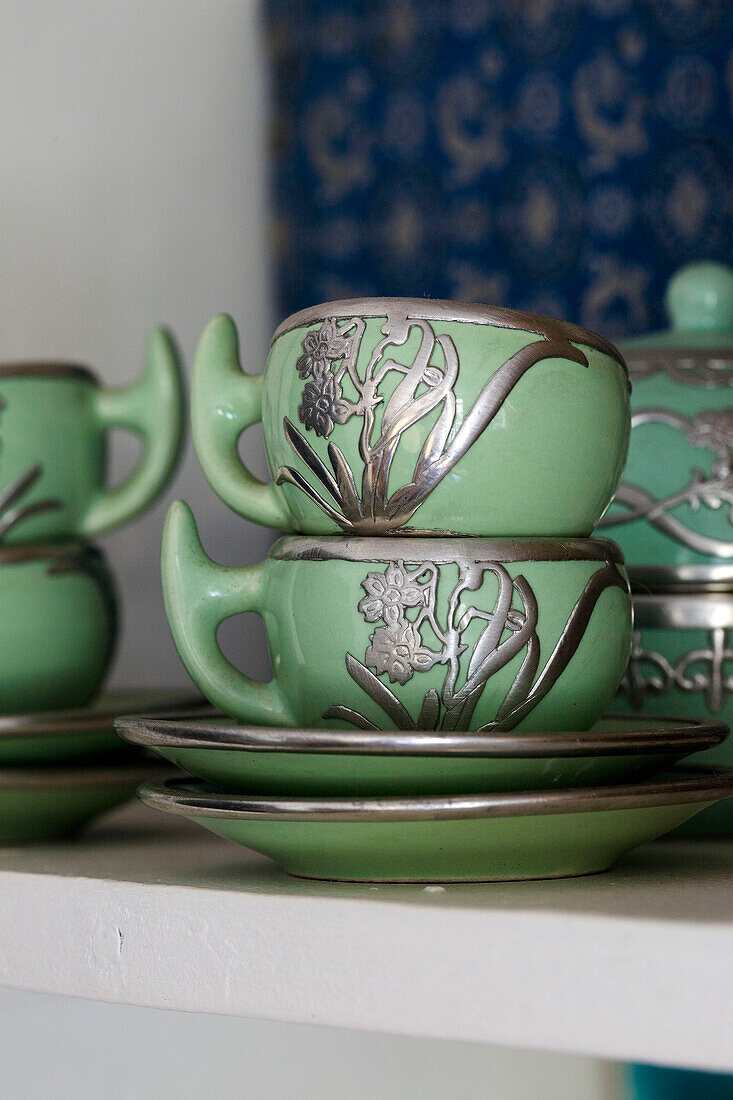 Grüne Teetassen mit silbernen Ornamenten auf einem Regal in einem Londoner Haus UK