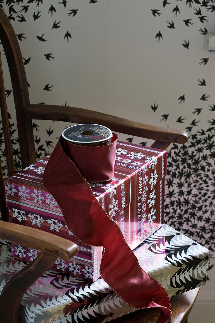 Burgunderfarbene Schleife und Weihnachtsgeschenke auf einem Stuhl in einem Londoner Haus UK