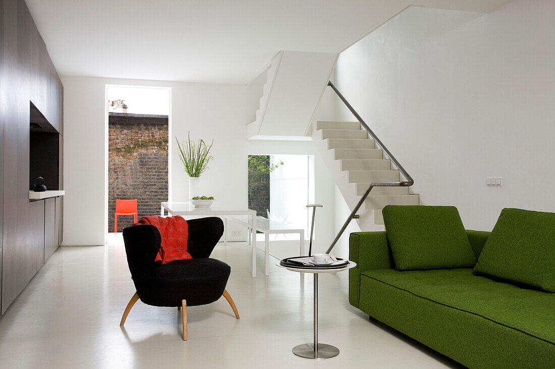 Limonengrünes Sofa und kleiner schwarzer Stuhl in offenem Interieur einer modernen Londoner Wohnung, England, UK
