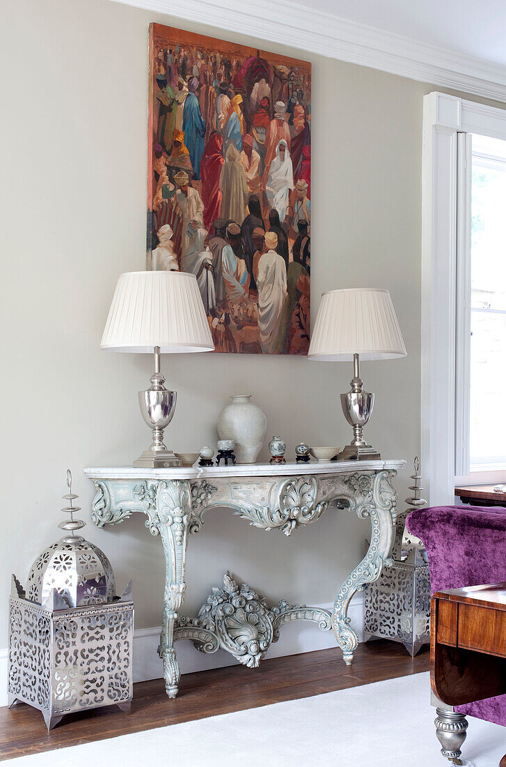 Silver lamps and artwork with purple sofa in living room of country house