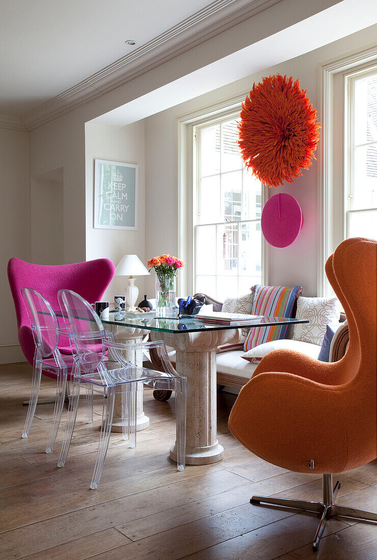 Glass topped dining table and Ghost chairs at sash windows in dining room
