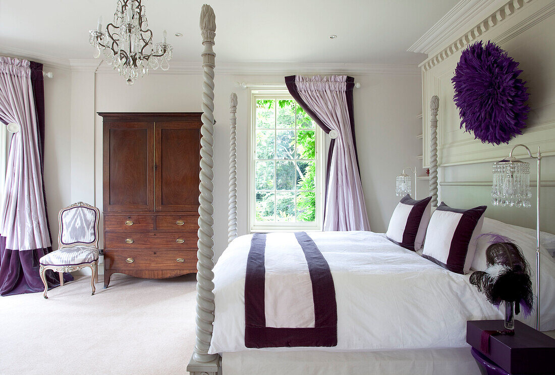 Wooden wardrobe in classic master bedroom upholstered in purple and lilac with carved bedposts