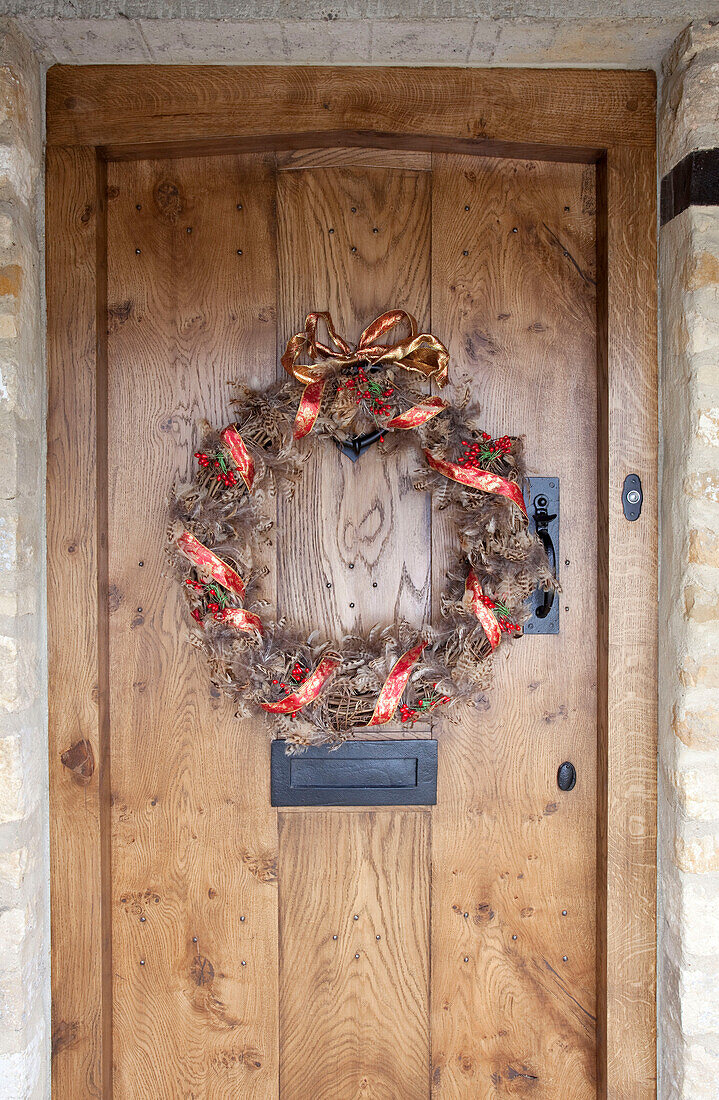 Christmas wreath on wooden doorway of Cotswolds home UK