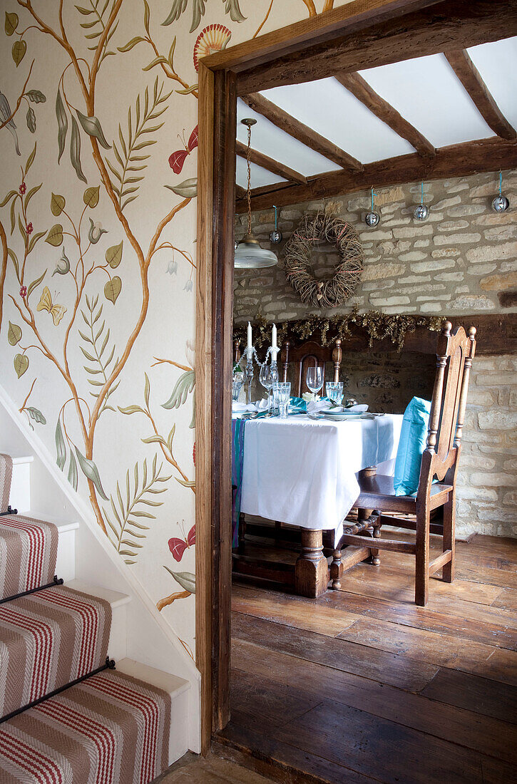 Nature inspired wallpaper and view through doorway to dining room of Cotswolds home UK