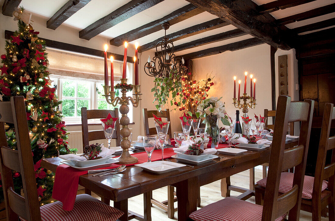 Christmas table with lit candles in timber framed Sussex home UK