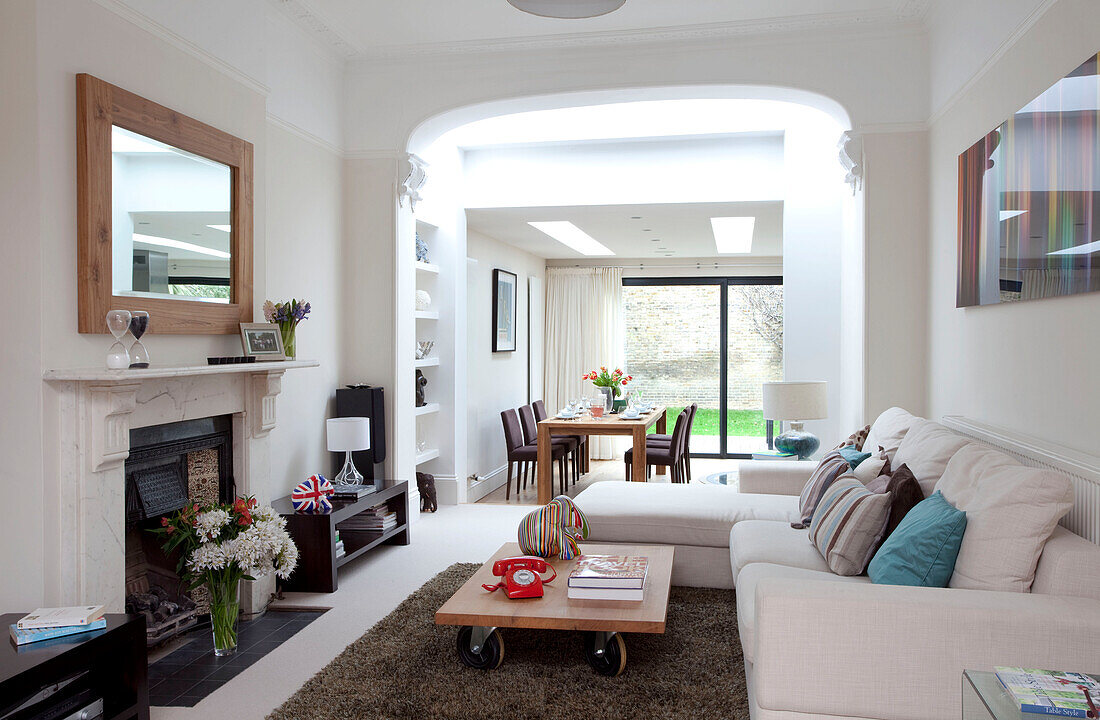 White corner sofa with coffee table at fireplace in double room of contemporary London home, UK