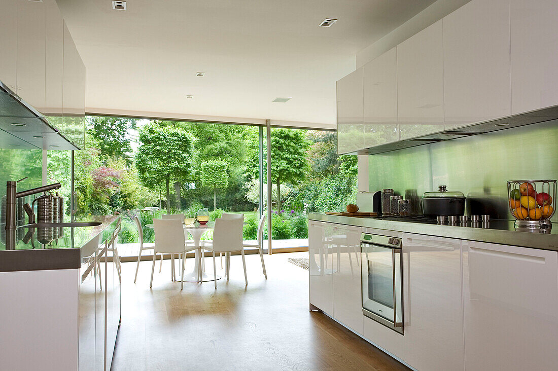Offene Pantry-Küche und Tisch mit Blick auf den Garten eines modernen Hauses in London, England, UK