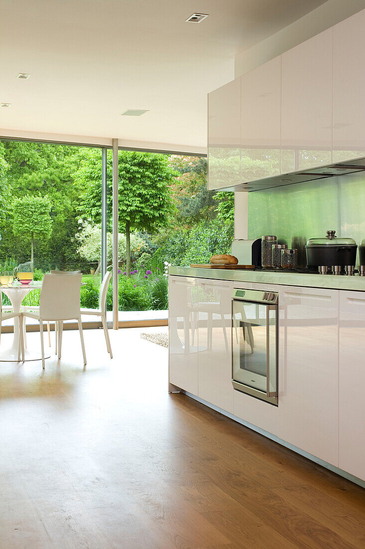 Saucepan on hob in white fitted open plan kitchen of contemporary London home, England, UK