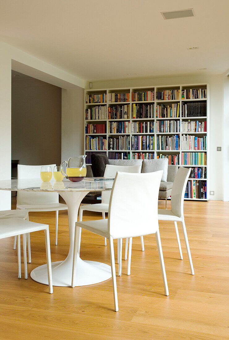Sockeltisch und Stühle mit Bücherregal in einem Haus in London, England, UK