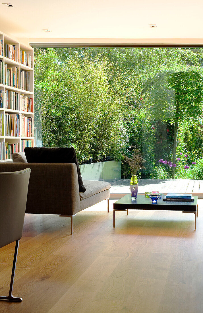 Chaiselongue und Bücherregal an einem Fenster mit Blick auf den Garten in einem Londoner Haus, England, UK