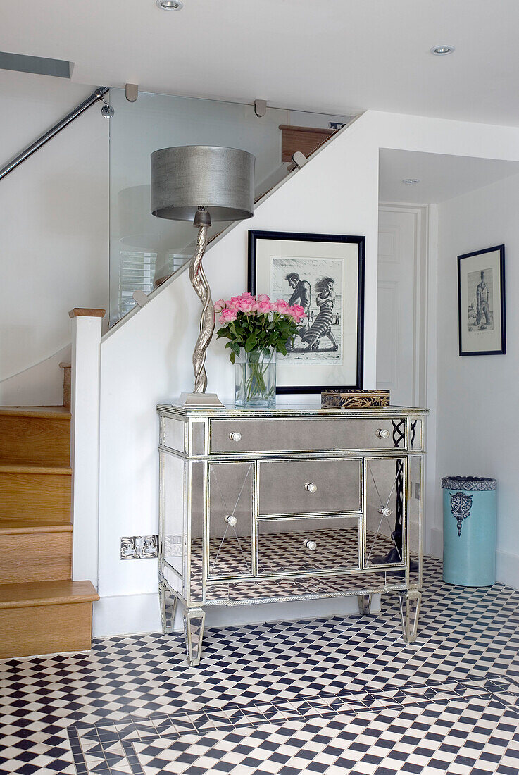 Silver lamp on mirrored sideboard in chequered hallway of Wepham home Sussex UK