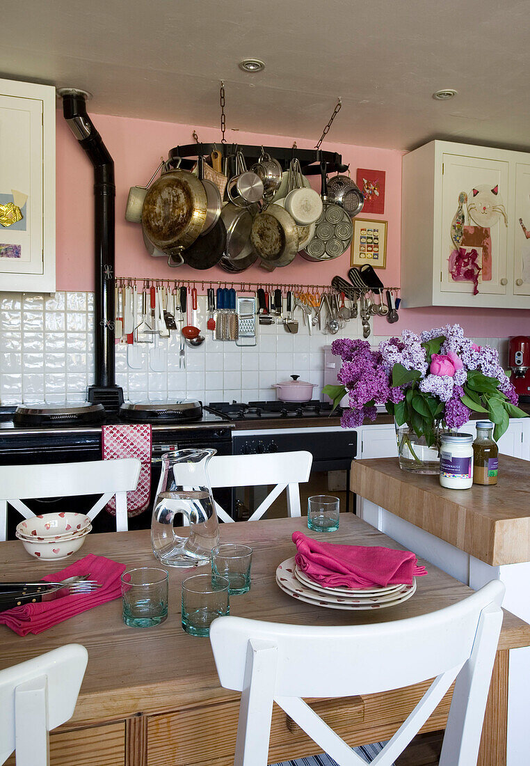 Pan rack in pink kitchen with glassware and napkins on table Suffolk UK