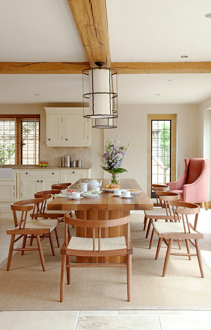 Wooden table and chairs in open plan kitchen of beamed Cotswolds home UK