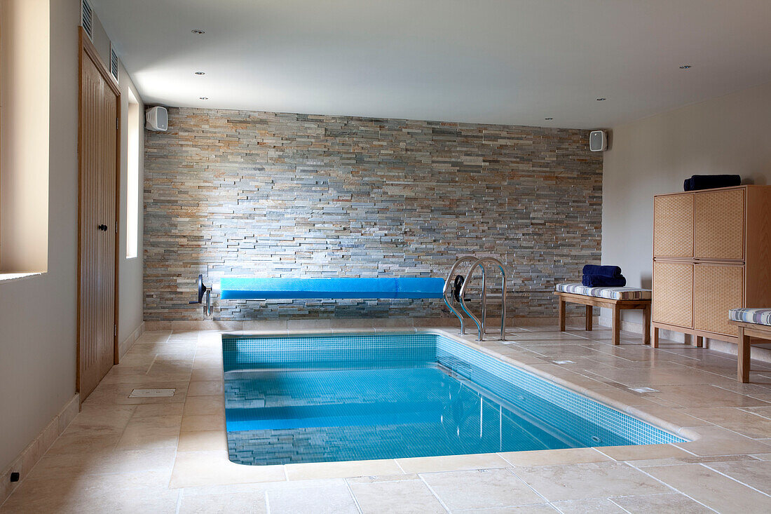 Swimmingpool mit freiliegender Steinmauer in einem Haus in den Cotswolds UK