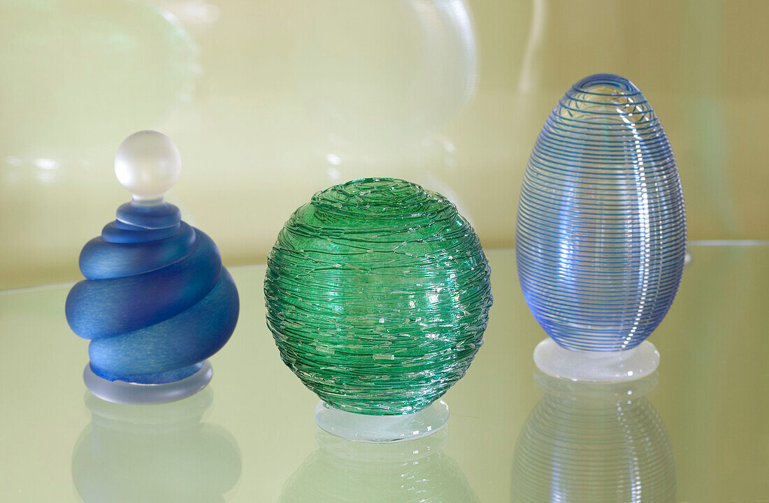 Blue and green glass objects on a glass shelf