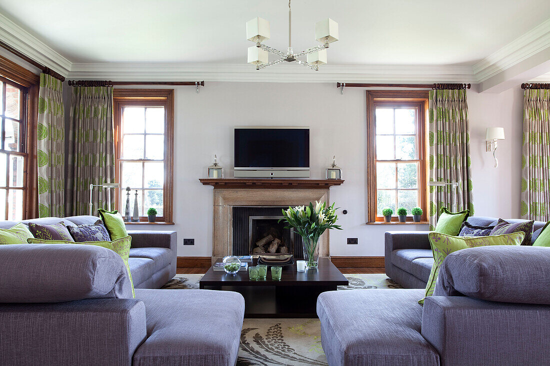 Lindgrüne Kissen und fliederfarbene Sofas in einem Wohnzimmer in Suffolk, UK