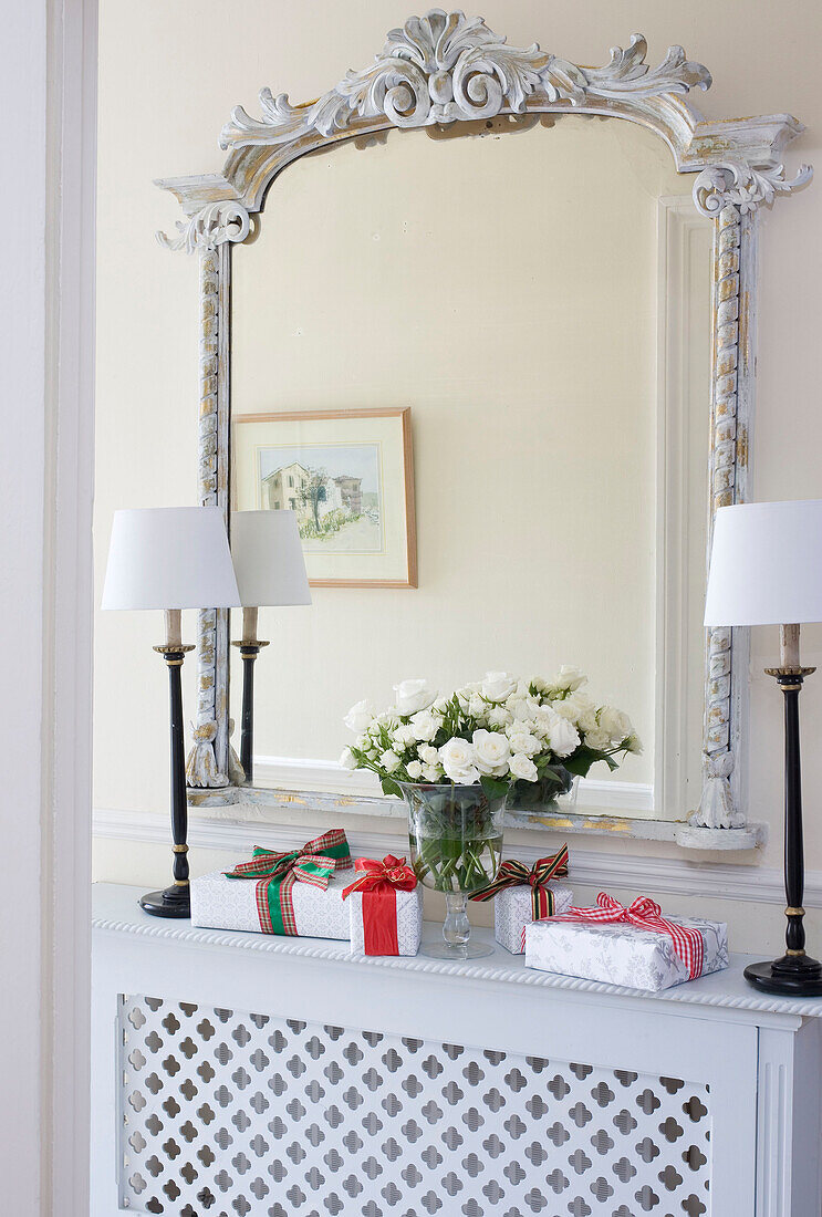 Geschnitzter antiker Spiegel mit passenden Lampen und Weihnachtsgeschenken über dem Heizkörper in einem Londoner Haus, UK