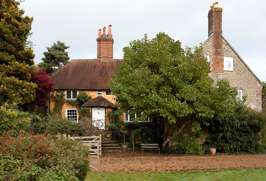 Bauernhaus aus Backstein mit Schotterauffahrt zwischen Bäumen im ländlichen Sussex, England, UK