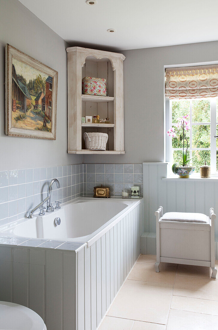 Hellblau getäfelte Badewanne mit gefliester Einfassung in einem Bauernhaus in Sussex, Vereinigtes Königreich