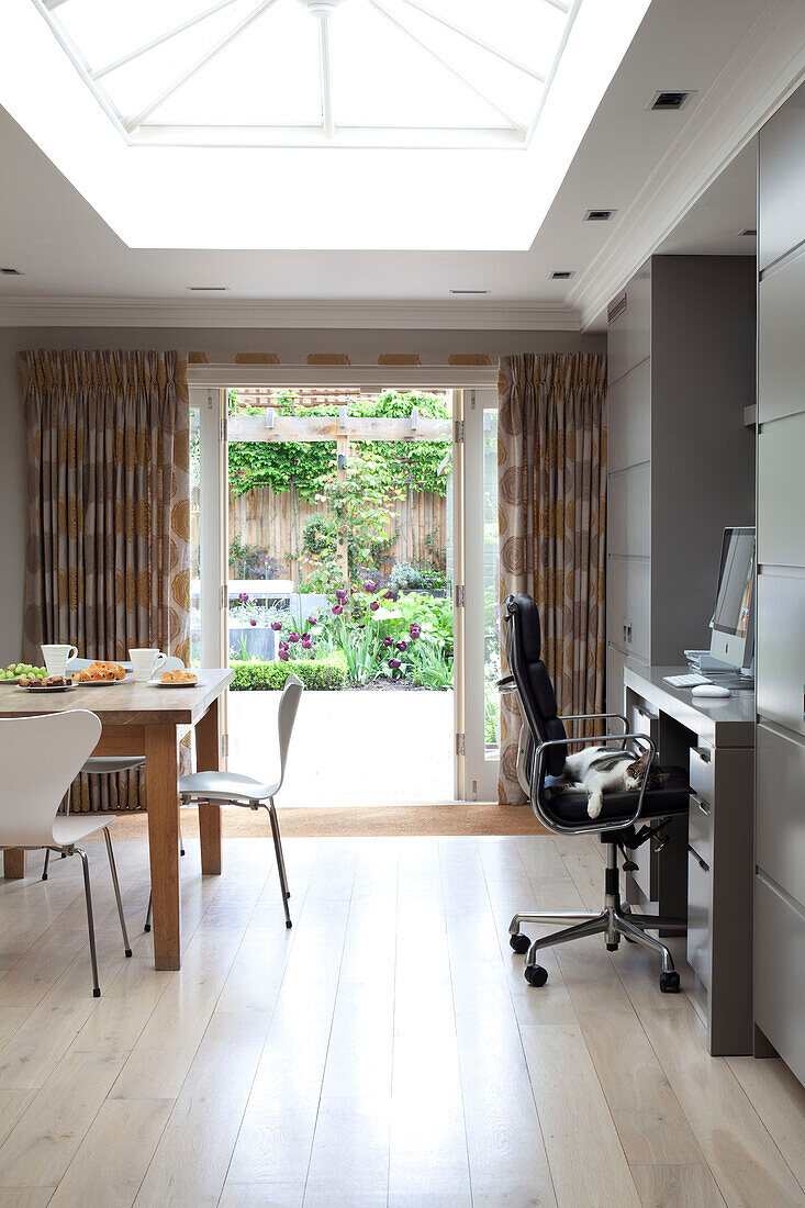 Bürostuhl an Schreibtisch und Tisch in einem offenen Anbau eines modernen Hauses in London, UK