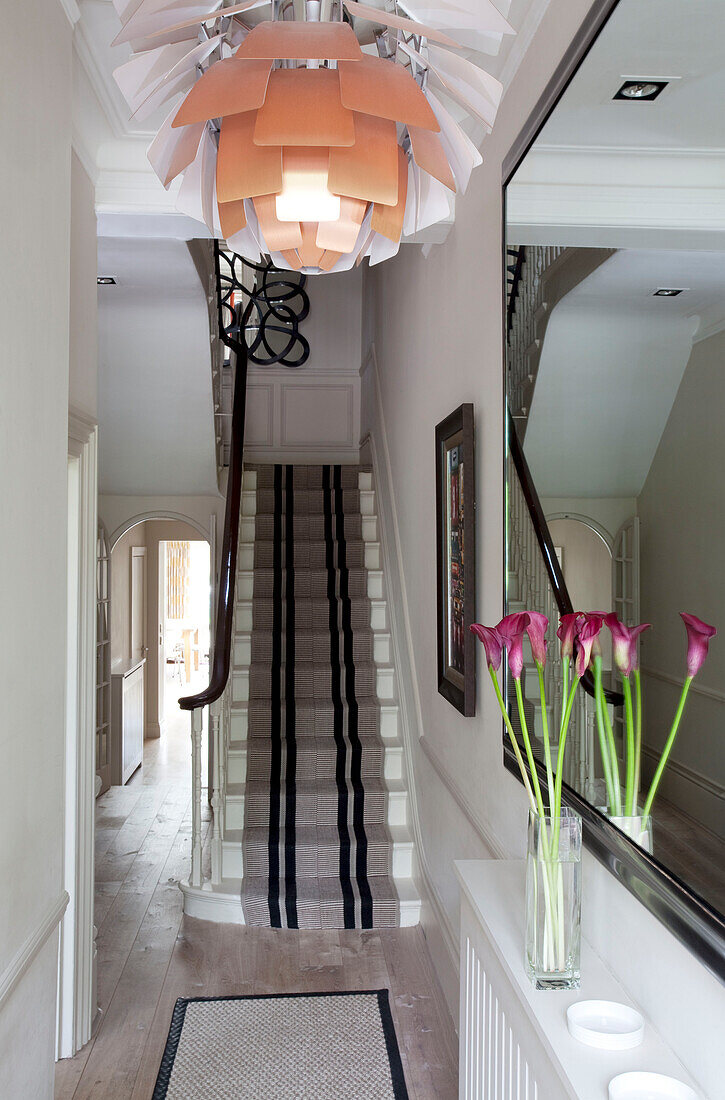 Geblümter Deckenlampenschirm im Flur eines modernen Londoner Hauses mit Teppichboden im Treppenhaus, UK