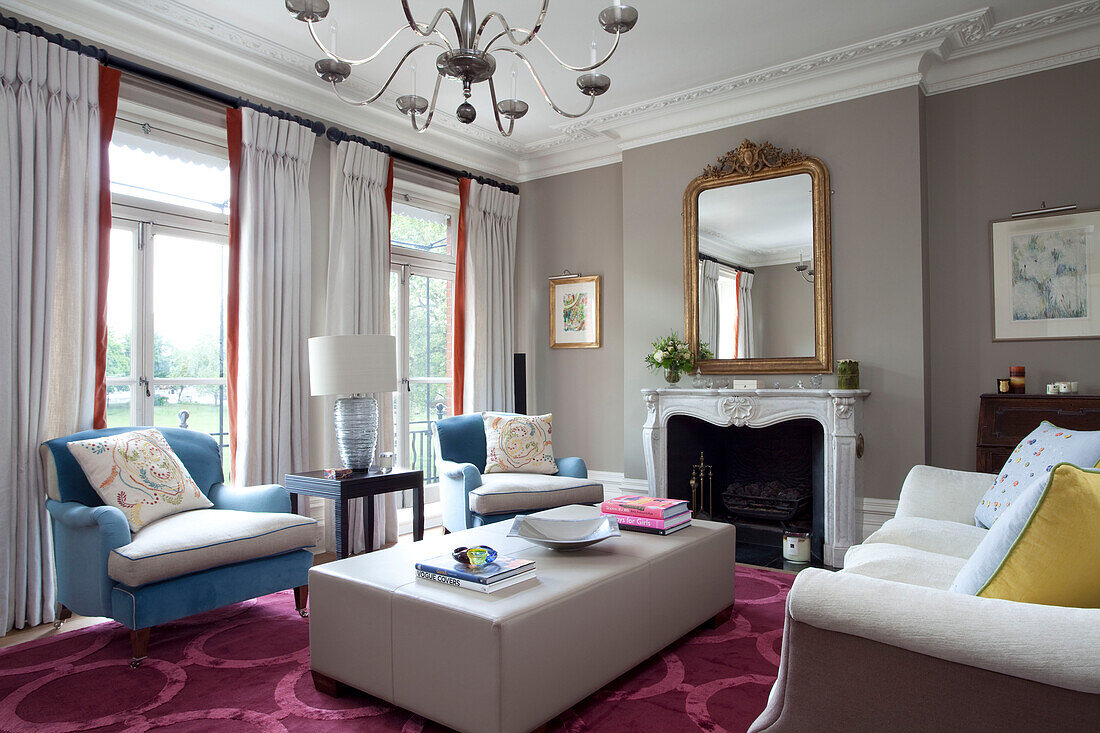 Passende blaue Sessel mit Lederhocker im Wohnzimmer mit rosa Teppich, modernes Haus in London, UK