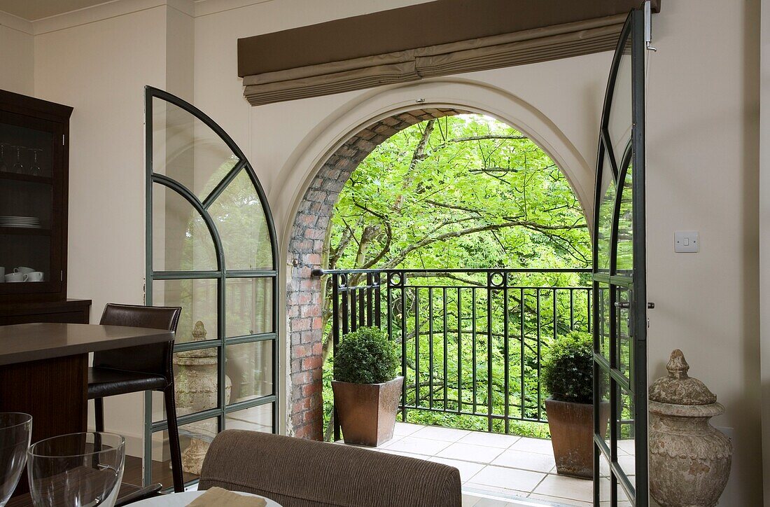 View through arched double doors to balcony exterior of contemporary Somerset home, England, UK