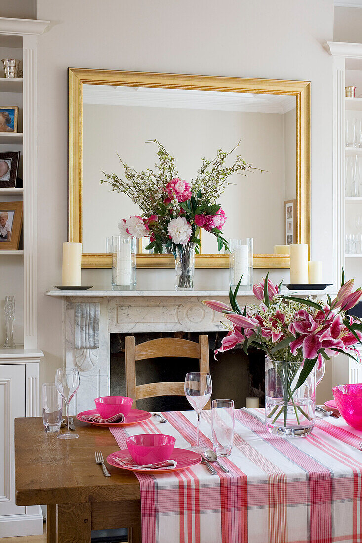 Pink homeware on checked tablecloth with gilt mirror in London dining room UK