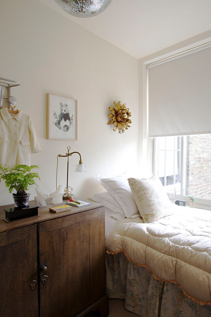 Einzelbett mit Bettdecke und hölzernem Nachttisch am Fenster eines Londoner Hauses UK