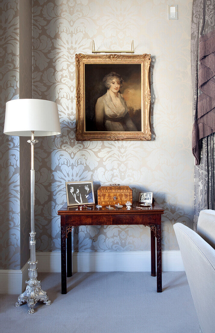 Artwork above wooden side table with standard lamp in contemporary London townhouse, UK