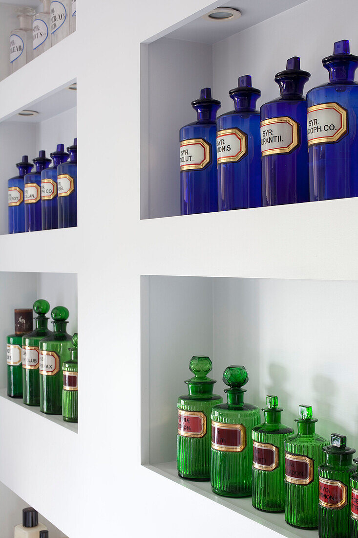 Blaue und grüne Medizinflaschen auf einem Regal in einem modernen Londoner Stadthaus, UK